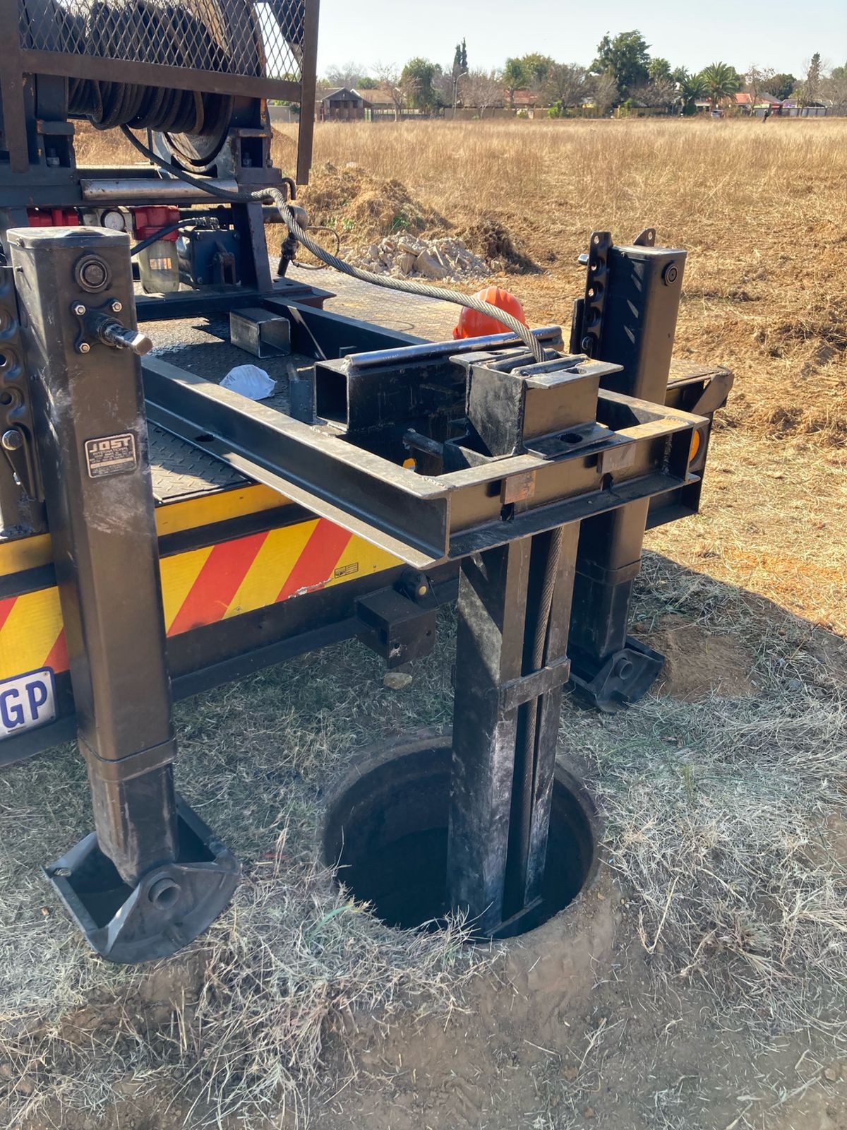 Crane lowering equipment into a manhole